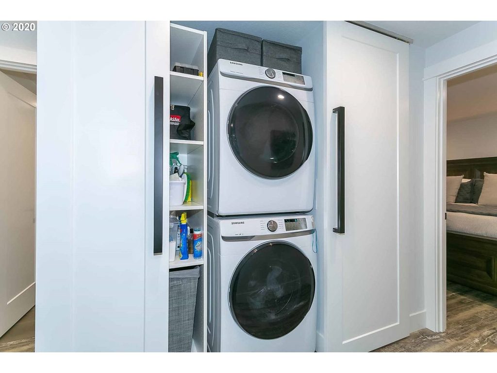 Remodeled laundry closet with stacked washer and dryer and built-in shelving