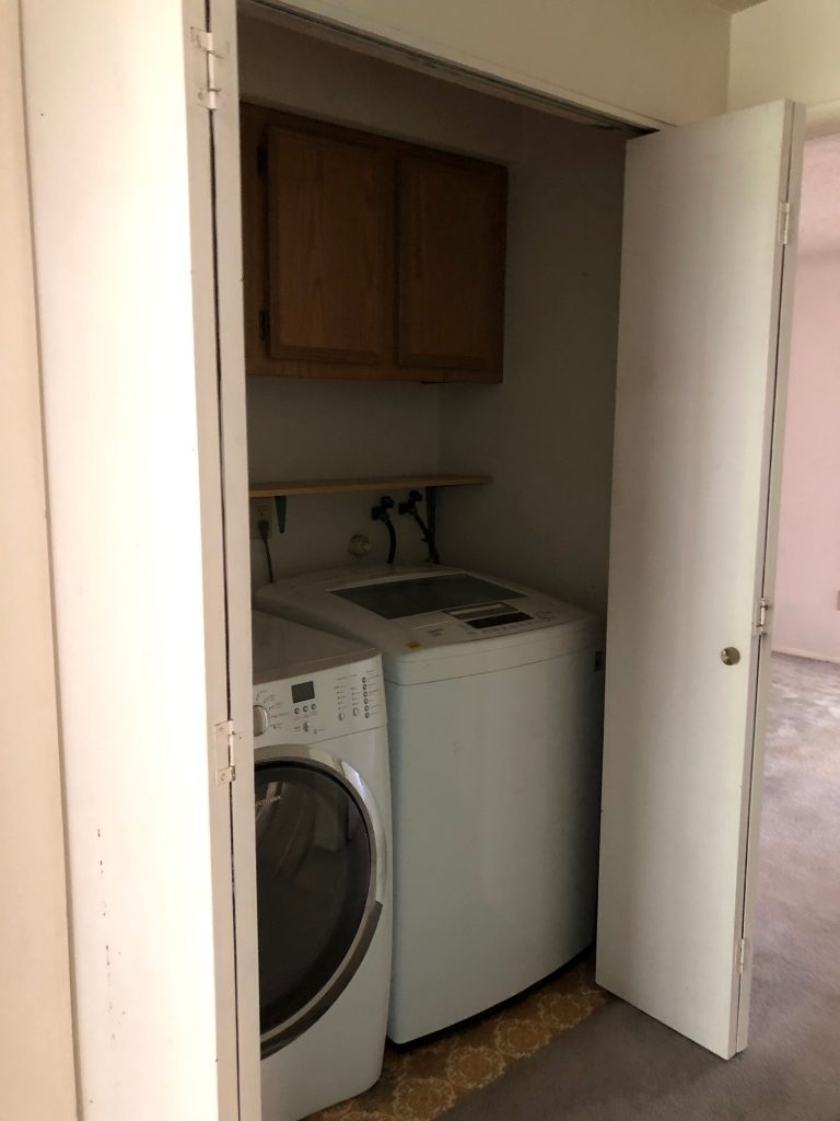 Laundry closet before remodel, with washer and dryer
